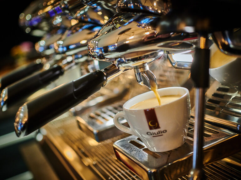 Eine Kaffeetasse wird von einer Maschine befüllt.