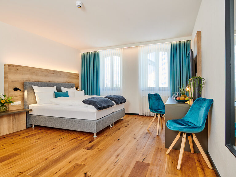 Das Zimmer bietet ein gemütliches Doppelbett einen kleinen Schreibtisch und einen Fernseher.